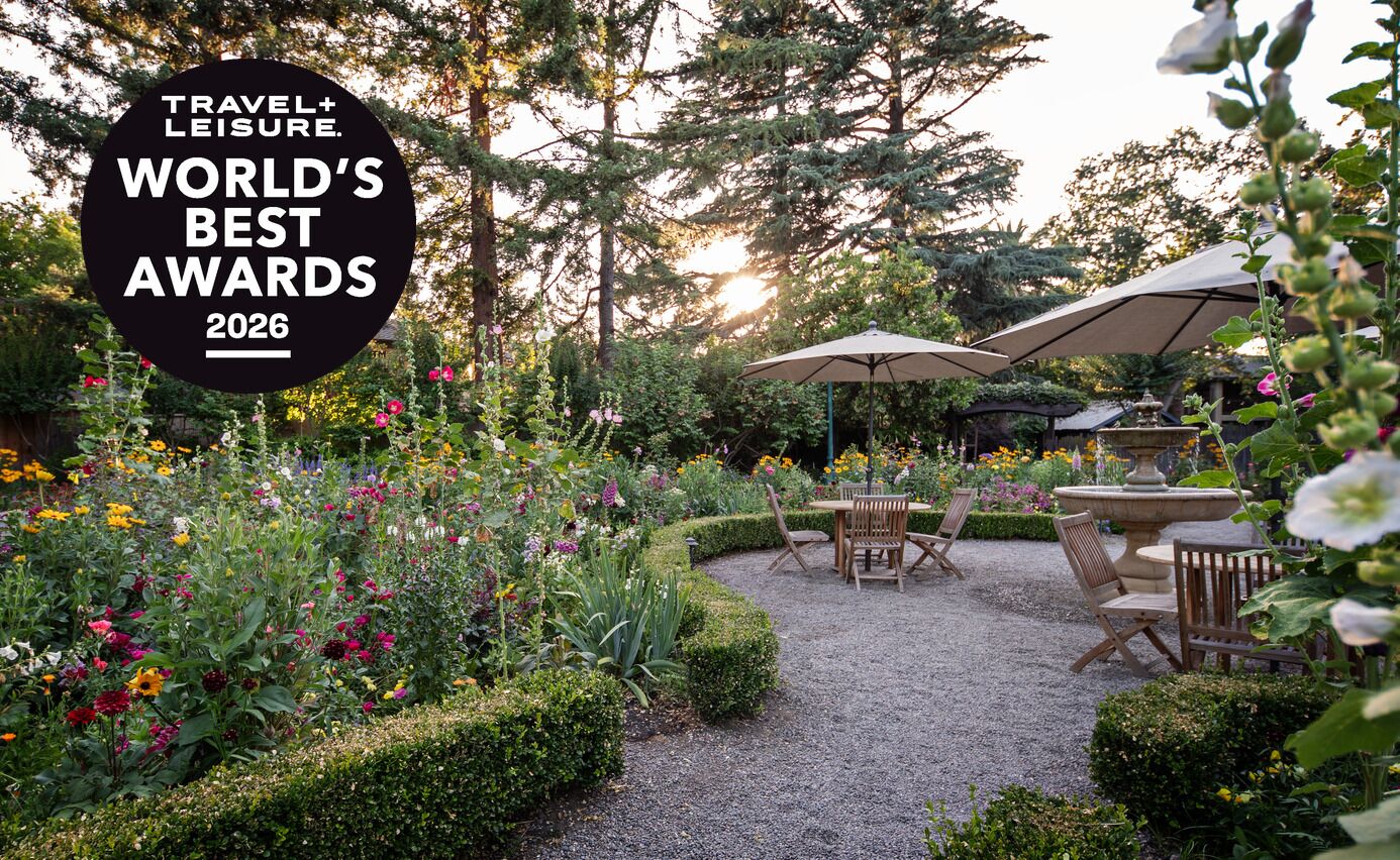 The flower garden at Appellation Lodi – Wine & Roses Resort and Spa at golden hour, with umbrellas over café tables and a stone fountain, and the Travel + Leisure World's Best Awards 2026 seal