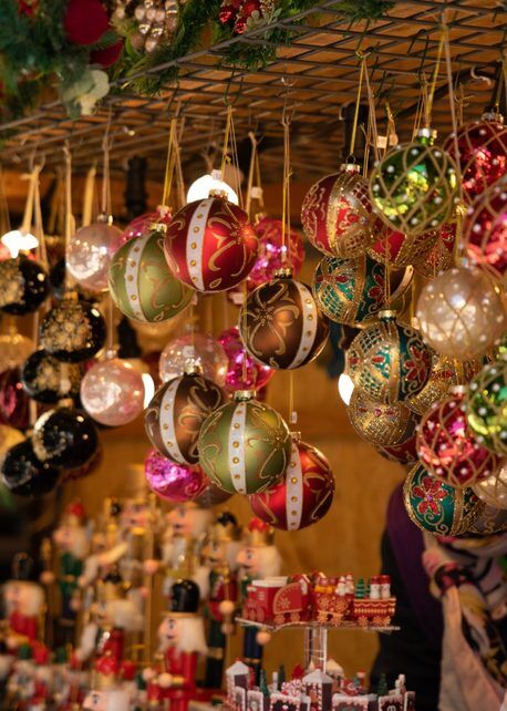 Hand-painted glass ornaments hang above a holiday market table of wooden nutcrackers