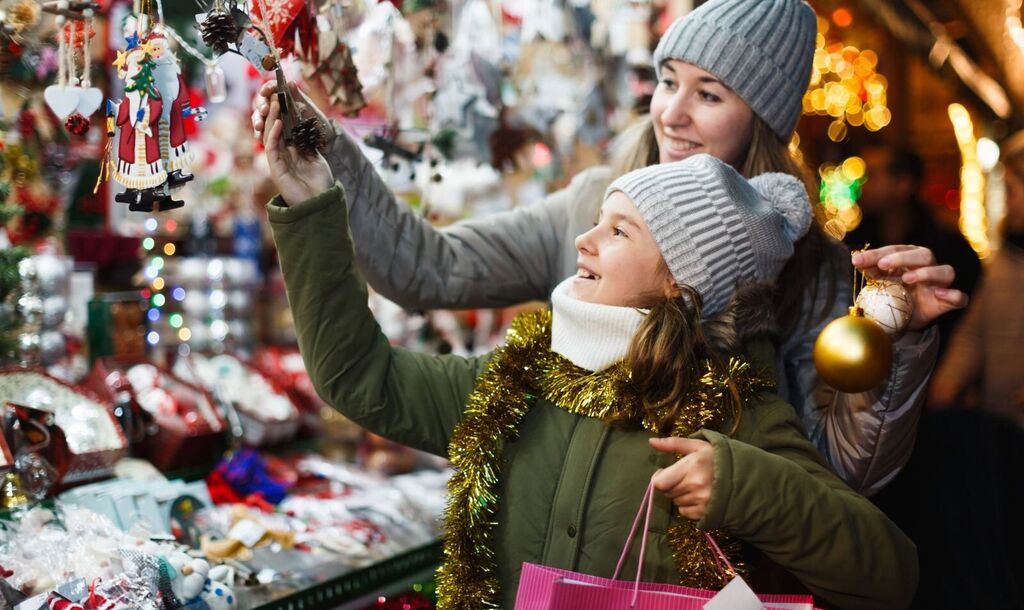 A mother and daughter choose ornaments at a holiday market