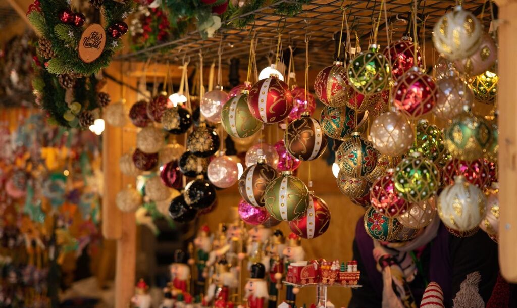 Hand-painted glass ornaments hang above a holiday market table of wooden nutcrackers