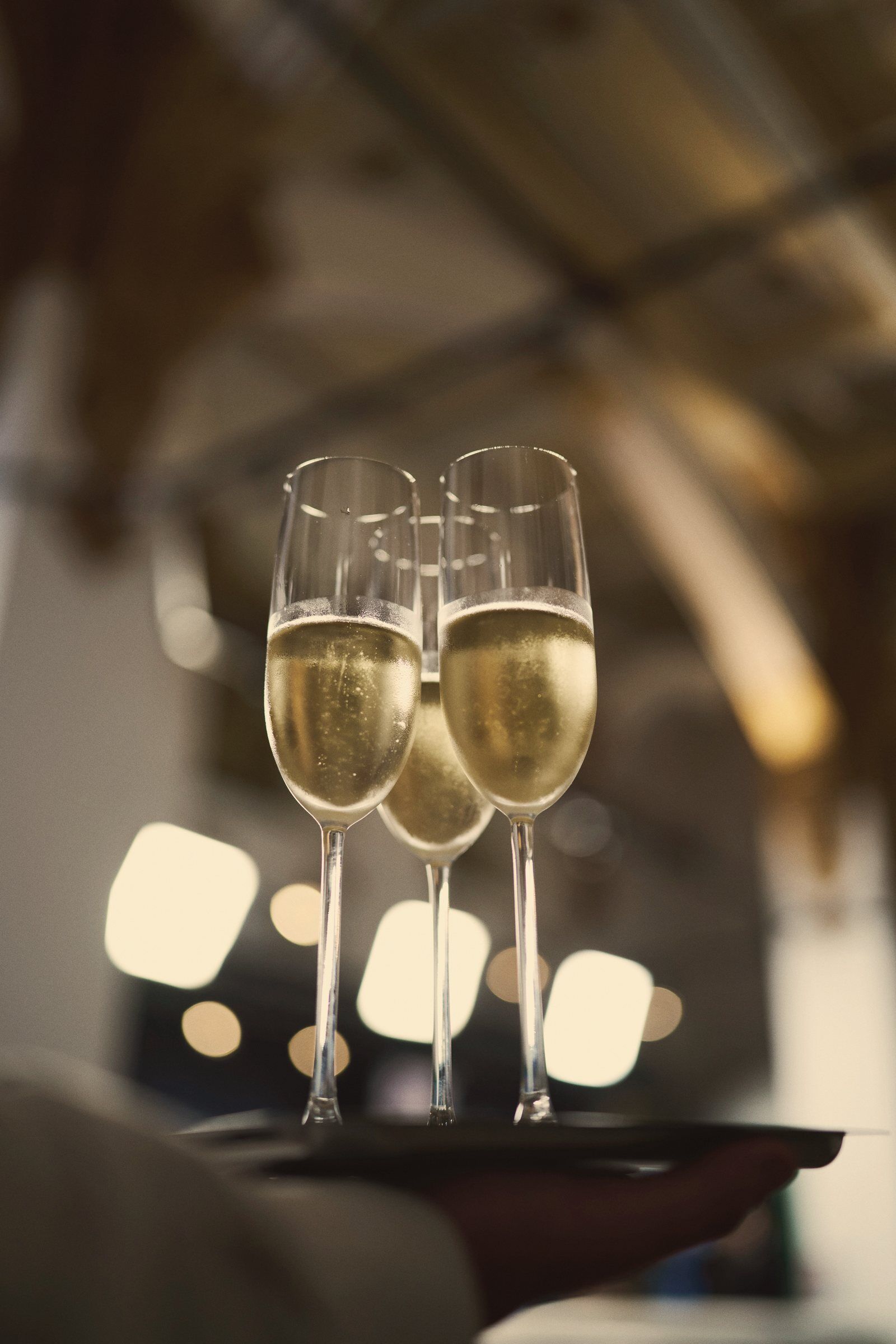 Three flutes of Lodi sparkling wine on a server's tray at a New Year's Eve celebration